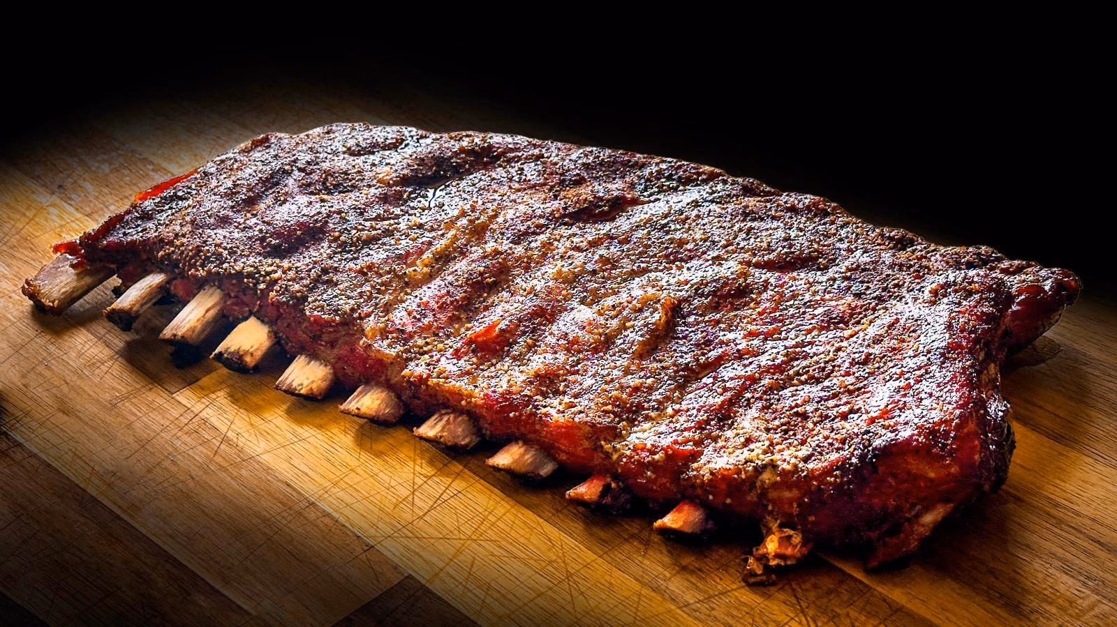 Rack entier de ribs de porc fumés au bois, croûte d’épices caramélisée