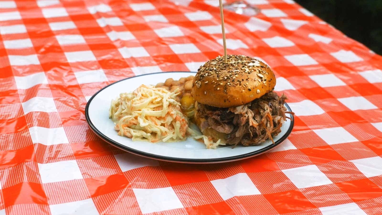 Assiette de burger pulled pork servie sur une table en extérieur